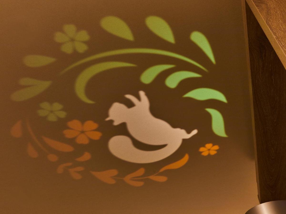Hotel Grand Nikko Tokyo Bay Maihama Urayasu Esterno foto The photo shows a colorful projection on a surface that includes a playful illustration. The design features a white silhouette of a squirrel in a lively pose, surrounded by decorative elements like green leaves and flowers in shades of orange and ye