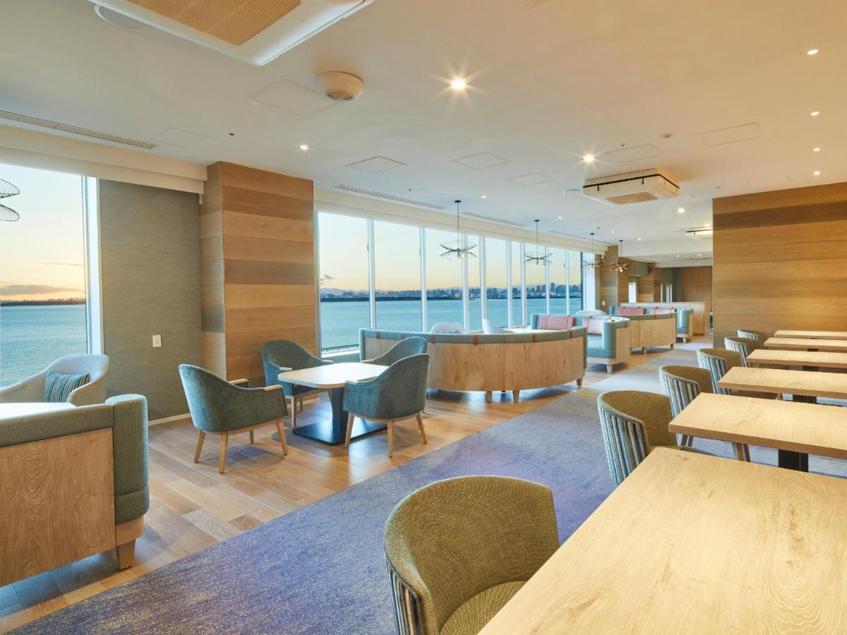 Hotel Grand Nikko Tokyo Bay Maihama Urayasu Esterno foto The photo shows a modern interior space, likely a dining or lounge area. It features large windows that offer a view of the water, allowing natural light to fill the room. The decor includes wooden walls and stylish, comfortable furniture, with sever