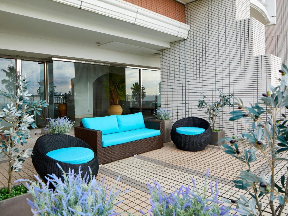 Hotel Grand Nikko Tokyo Bay Maihama Urayasu Esterno foto The image shows a stylish outdoor seating area. There is a brown couch with turquoise cushions, complemented by two matching round chairs nearby. The seating is arranged on a tiled patio, which is bordered by planters featuring lavender flowers and g