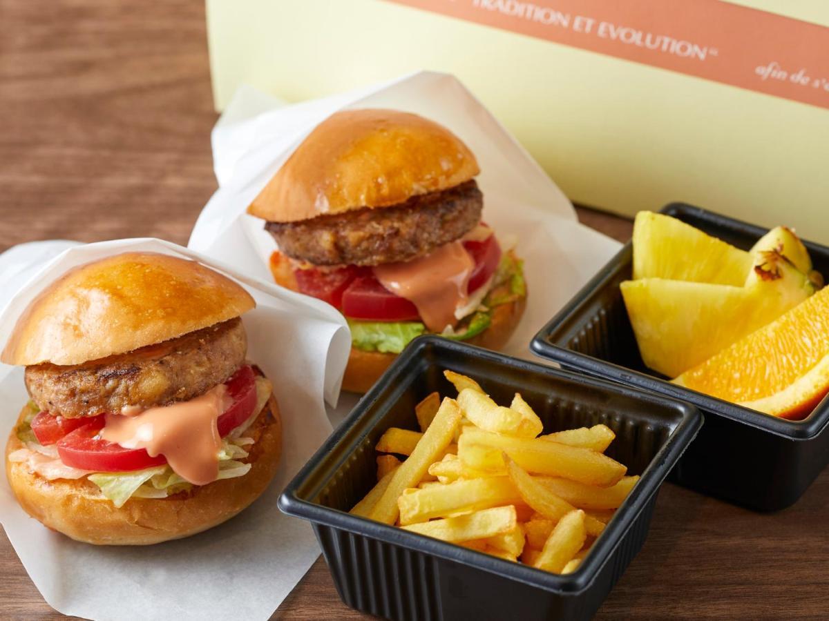 Hotel Grand Nikko Tokyo Bay Maihama Urayasu Esterno foto The photo shows two small burgers placed on a white background, each with a golden-brown bun, a fried patty, lettuce, tomato, and a creamy sauce. Alongside the burgers, there are two containers: one holding a serving of french fries and the other con