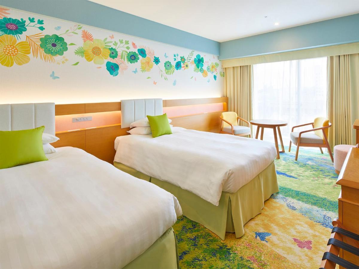 Hotel Grand Nikko Tokyo Bay Maihama Urayasu Esterno foto The photo shows a brightly decorated hotel room featuring two twin beds with white linens and light green accents. Above the beds is a colorful floral mural that adds a cheerful touch to the space. There is a small table and chairs by the window, whi