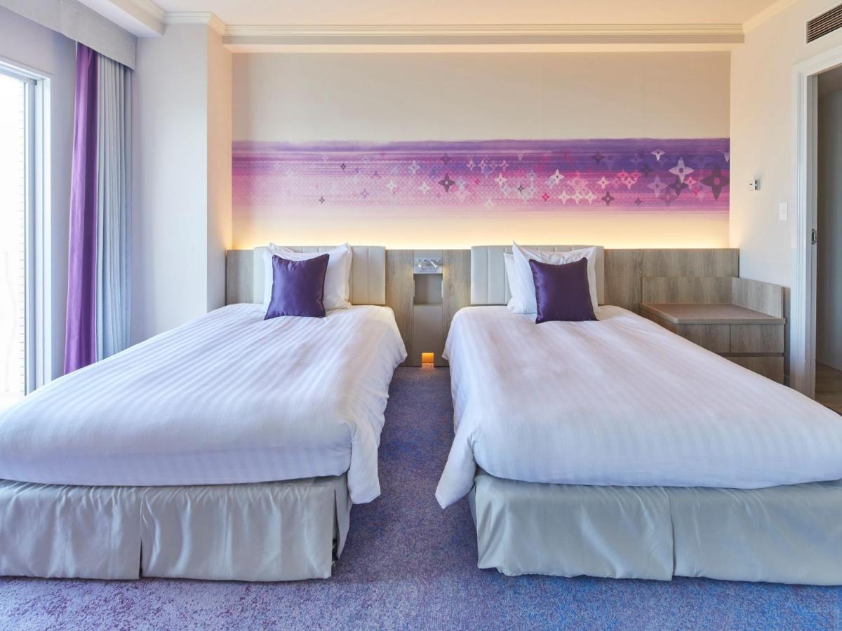 Hotel Grand Nikko Tokyo Bay Maihama Urayasu Esterno foto The photo shows a hotel room featuring two twin beds with white bedding and purple accent pillows. The beds are positioned next to each other, with a light-colored headboard. Behind the beds, there is a decorative wall with a gradient of purple hues.