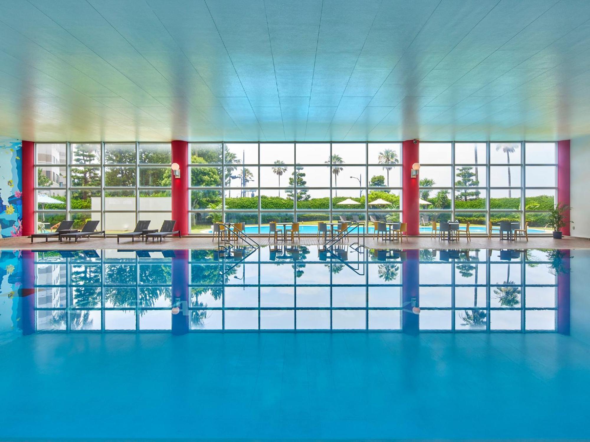 Hotel Grand Nikko Tokyo Bay Maihama Urayasu Esterno foto The photo shows an indoor swimming pool with bright blue water. The pool area is spacious, characterized by large windows that allow natural light to flood in, creating a vibrant atmosphere. The walls are painted in a soft color, with accents of red.