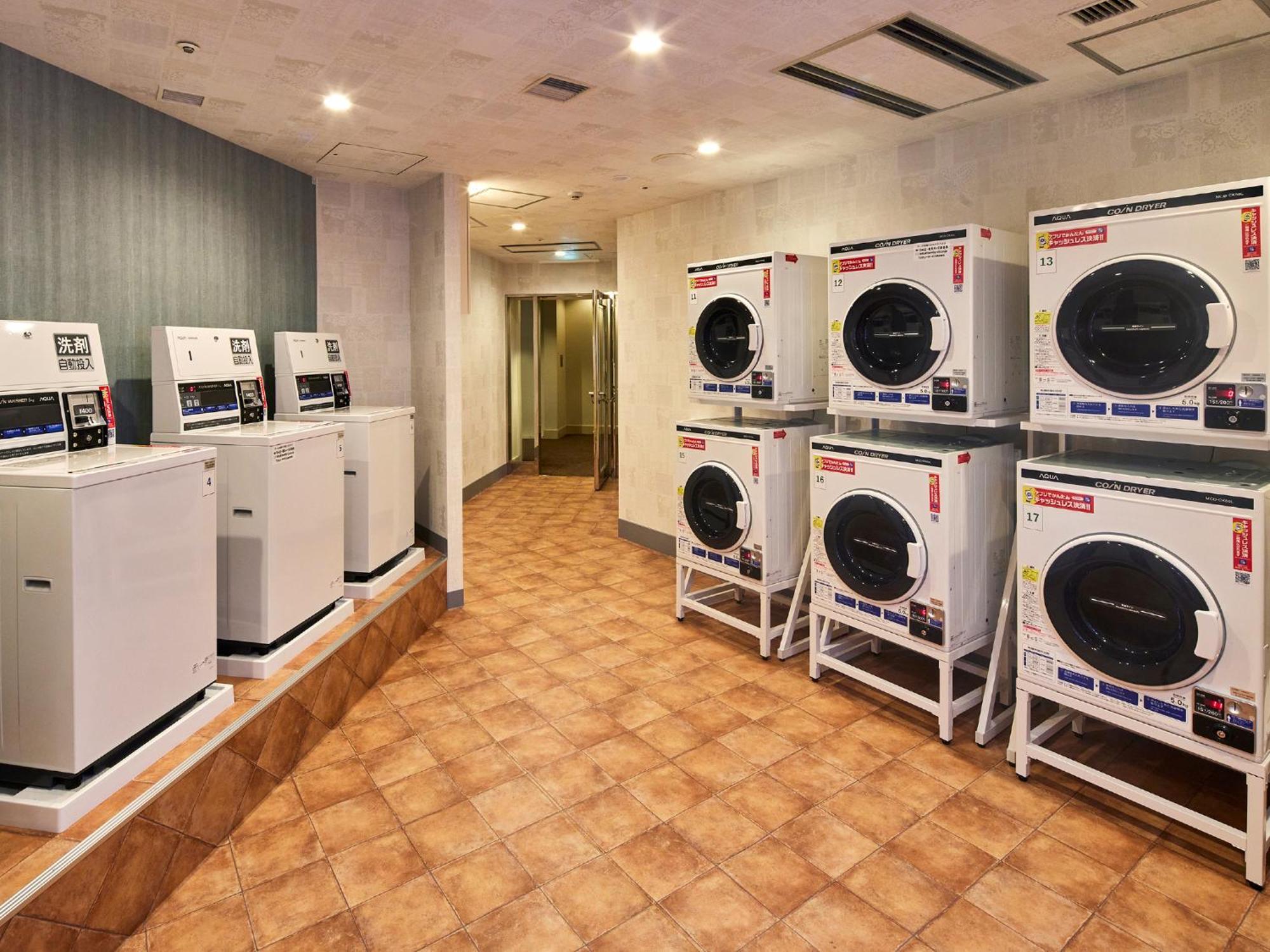 Hotel Grand Nikko Tokyo Bay Maihama Urayasu Esterno foto The photo shows a laundry room with several washing machines and dryers. On the left side, there are five white washing machines, and on the right side, there are four dryers. The machines are arranged in a clean, tiled space with a neutral-colored w