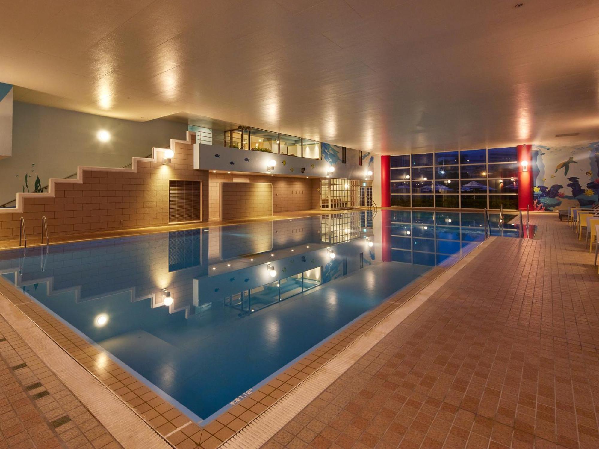 Hotel Grand Nikko Tokyo Bay Maihama Urayasu Esterno foto The photo shows an indoor swimming pool area. The pool features a calm blue water surface and is surrounded by tiled flooring. There is a staircase leading to a higher level, likely providing access to a lounge or seating area. Large windows allow na