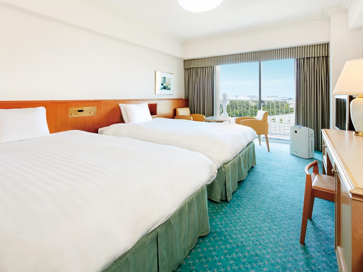 Hotel Grand Nikko Tokyo Bay Maihama Urayasu Esterno foto The photo shows a hotel room featuring two twin beds with white bedding. The walls are painted in light colors, and there’s a window that offers a view outside, letting in natural light. A small table and chairs are visible near the window, as well a